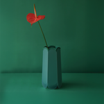 POTR Letterbox Vase with a red flower against a green background, showcasing its origami-inspired design.